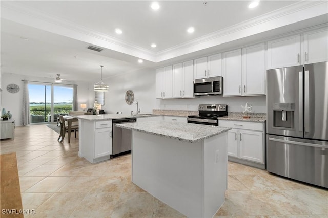 kitchen featuring appliances with stainless steel finishes, hanging light fixtures, white cabinets, a kitchen island, and kitchen peninsula