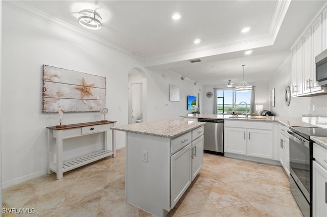 kitchen with appliances with stainless steel finishes, white cabinets, a kitchen island, sink, and light stone counters