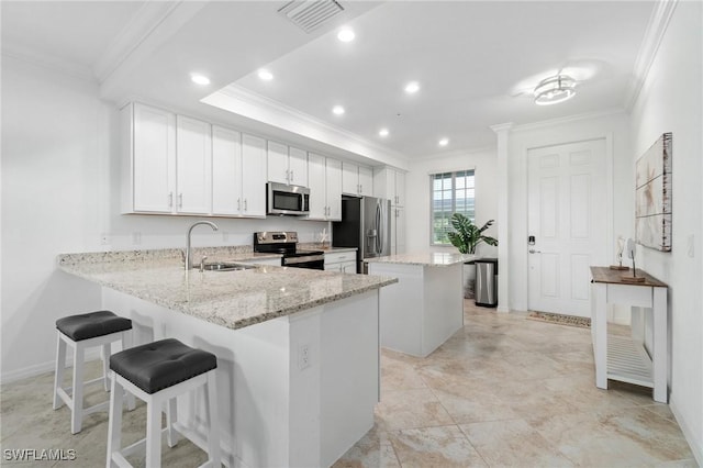 kitchen featuring a center island, a kitchen breakfast bar, white cabinets, kitchen peninsula, and stainless steel appliances