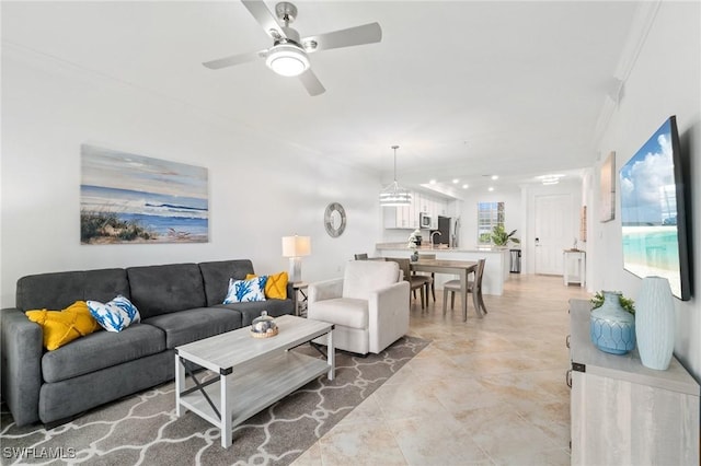 living room featuring ceiling fan, sink, and ornamental molding