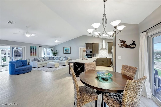 dining area featuring vaulted ceiling, ceiling fan with notable chandelier, and light hardwood / wood-style floors