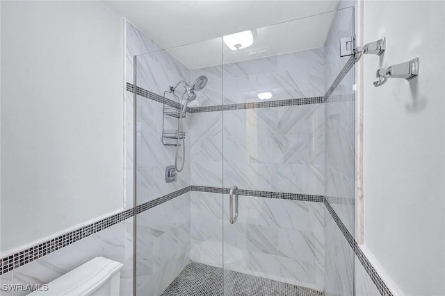 bathroom with toilet, a shower with shower door, and tile walls