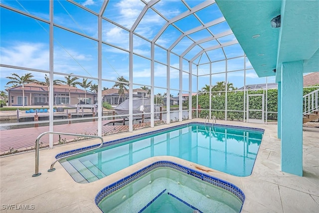 view of pool with a patio, glass enclosure, and an in ground hot tub