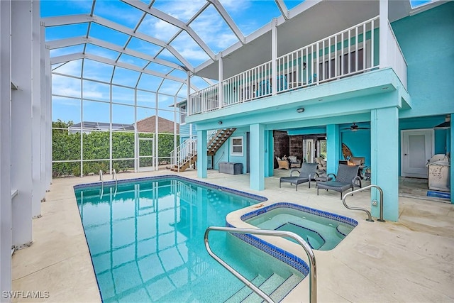 view of swimming pool featuring ceiling fan, glass enclosure, an outdoor living space, a patio area, and an in ground hot tub