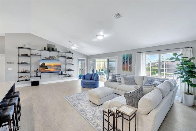 living room with ceiling fan, vaulted ceiling, light hardwood / wood-style floors, and a healthy amount of sunlight