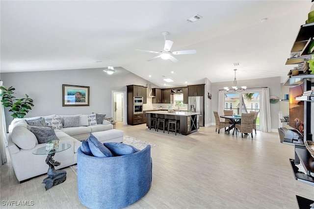 living room with lofted ceiling, ceiling fan with notable chandelier, and light wood-type flooring