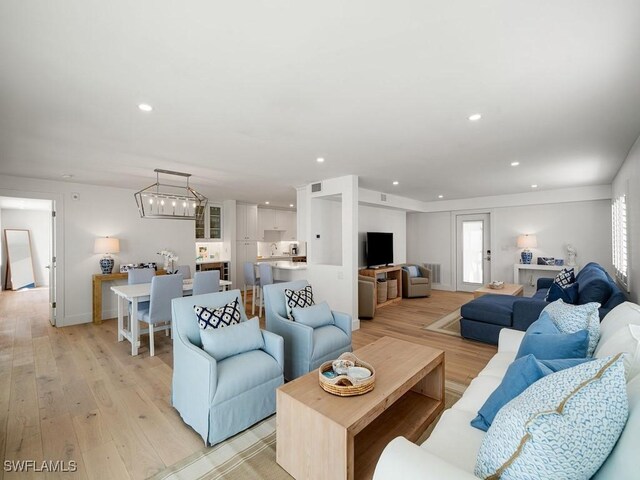 living room featuring an inviting chandelier and light wood-type flooring