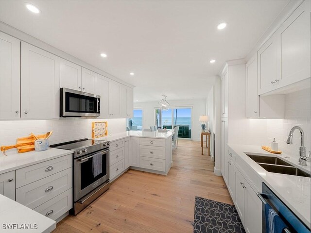 kitchen featuring white cabinetry, stainless steel appliances, sink, and light wood-type flooring