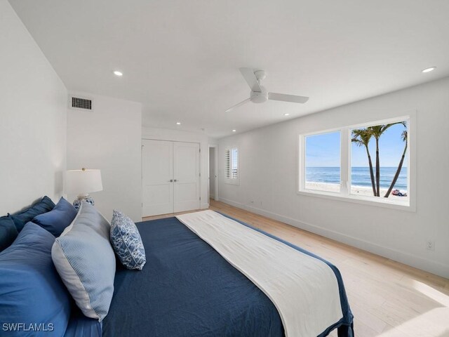 bedroom with a water view, ceiling fan, and light hardwood / wood-style flooring