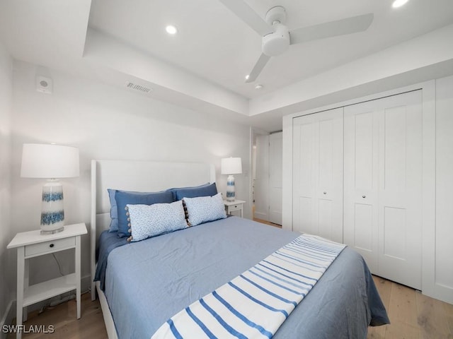 bedroom featuring a raised ceiling, light hardwood / wood-style floors, and a closet