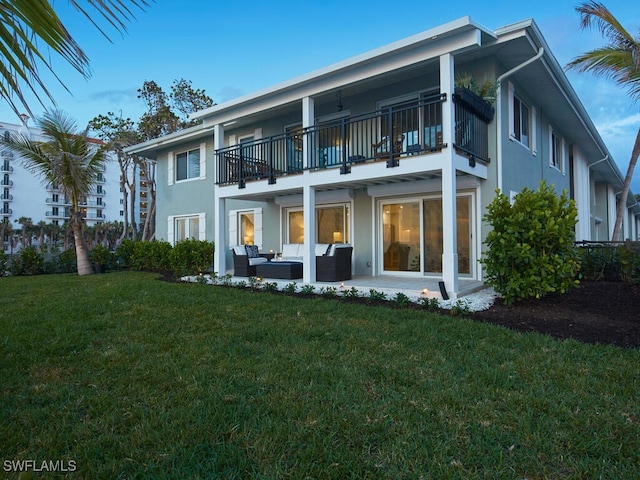 back of house with an outdoor living space, a balcony, and a yard