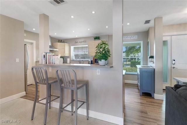 kitchen featuring sink, light hardwood / wood-style flooring, kitchen peninsula, and a healthy amount of sunlight