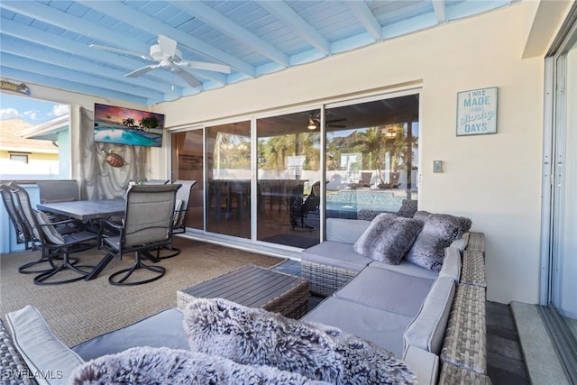 sunroom / solarium featuring beamed ceiling and ceiling fan