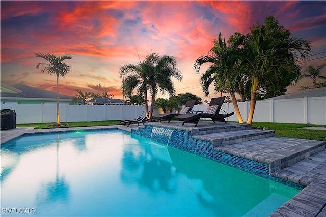 pool at dusk featuring pool water feature