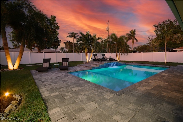 pool at dusk with pool water feature and a patio area