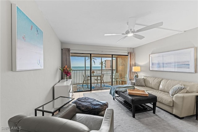 living room featuring ceiling fan and a water view