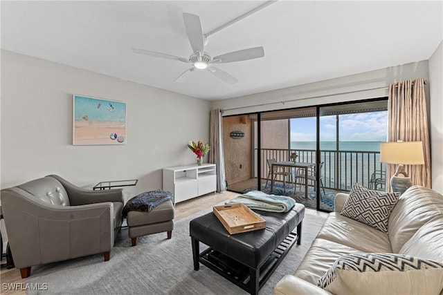 living room with ceiling fan, a water view, and hardwood / wood-style floors