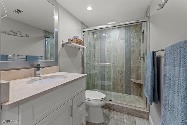 bathroom with toilet, vanity, and a shower with door