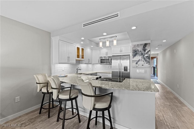 25850 Hickory Blvd Unit A-104, Bonita Springs, FL 34134 - kitchen featuring stainless steel appliances, a peninsula, a sink, white cabinets, and light stone countertops