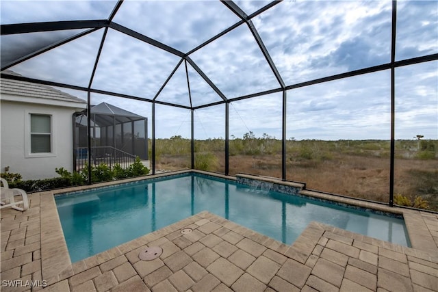 view of swimming pool with glass enclosure and a patio