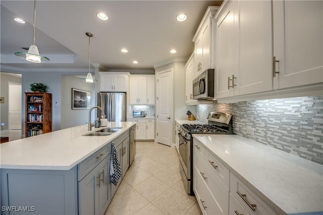 kitchen featuring stainless steel appliances, decorative backsplash, a kitchen island with sink, hanging light fixtures, and white cabinets