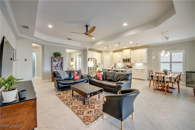 tiled living room featuring ceiling fan, crown molding, and a raised ceiling