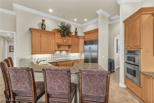 kitchen featuring appliances with stainless steel finishes, tasteful backsplash, a kitchen breakfast bar, sink, and kitchen peninsula