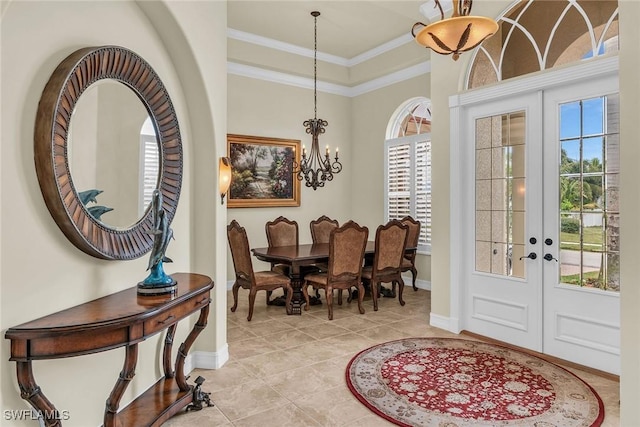 entrance foyer featuring plenty of natural light, a chandelier, ornamental molding, and french doors