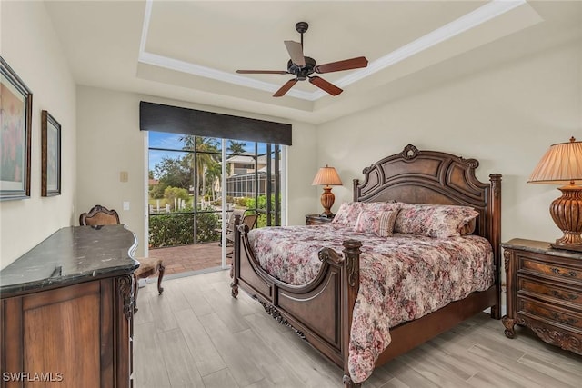 bedroom featuring ceiling fan, light hardwood / wood-style floors, a tray ceiling, and access to outside