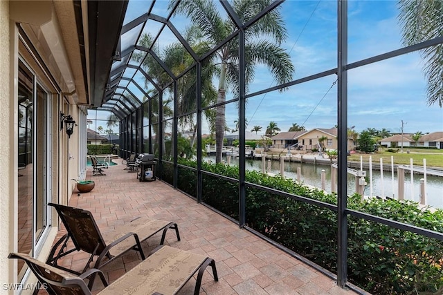 view of patio with a lanai and a water view