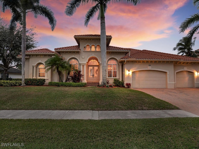 mediterranean / spanish-style house featuring a garage and a lawn