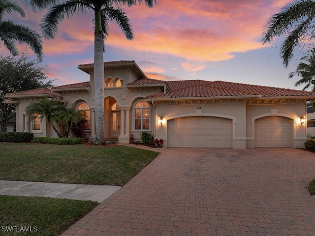 mediterranean / spanish home with a garage and a yard