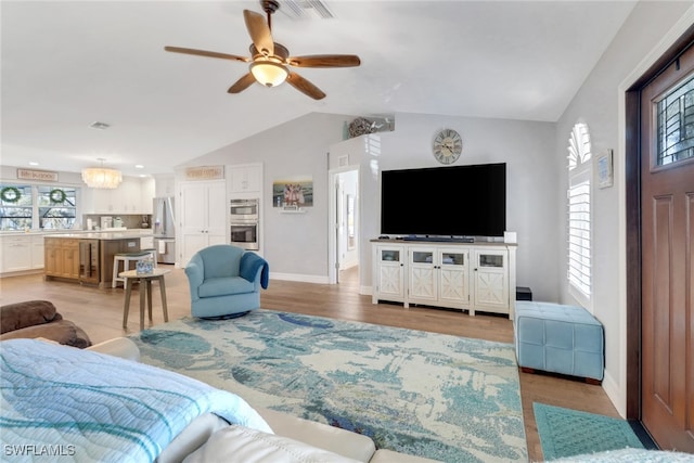 living room featuring ceiling fan, lofted ceiling, light wood-type flooring, and a wealth of natural light