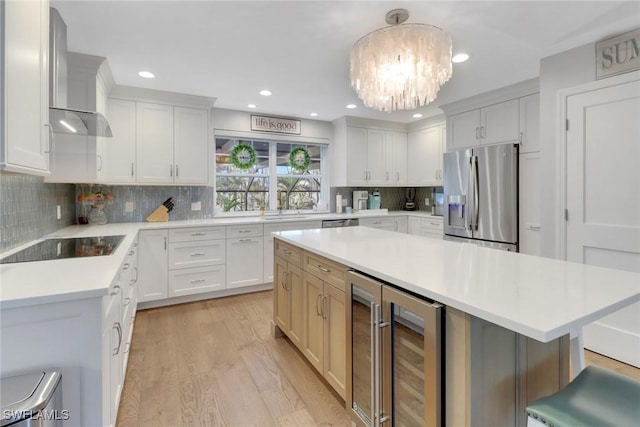 kitchen with appliances with stainless steel finishes, decorative light fixtures, white cabinetry, beverage cooler, and a center island