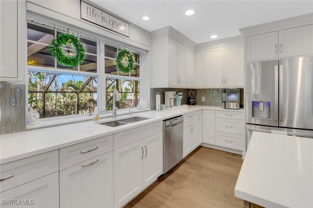 kitchen featuring appliances with stainless steel finishes, sink, decorative backsplash, and white cabinets