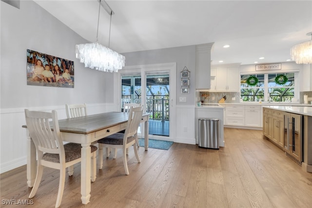 dining space with wine cooler, a chandelier, and light hardwood / wood-style floors