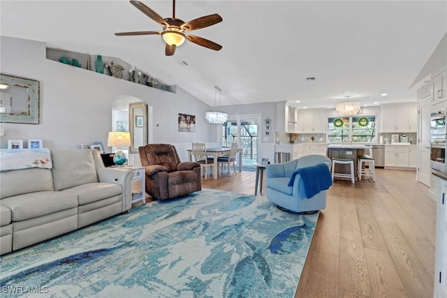 living room with ceiling fan with notable chandelier, vaulted ceiling, and light wood-type flooring