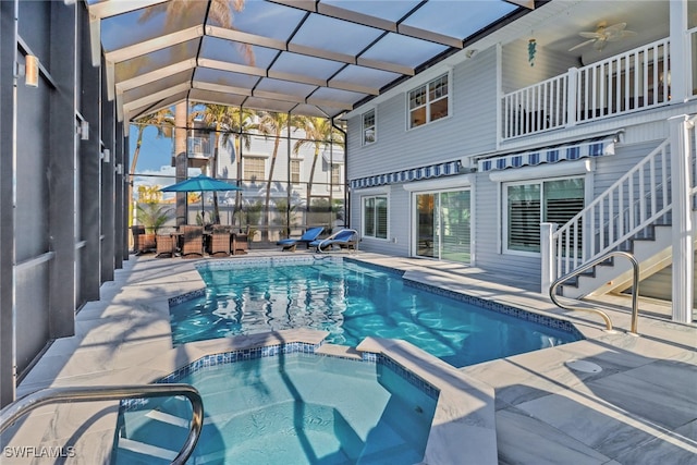 view of pool featuring an in ground hot tub, ceiling fan, glass enclosure, and a patio