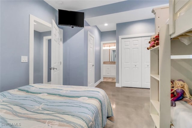 bedroom featuring a closet, ensuite bathroom, and concrete floors