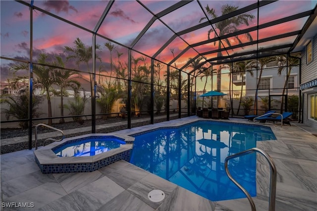 pool at dusk with a lanai, a patio area, and an in ground hot tub