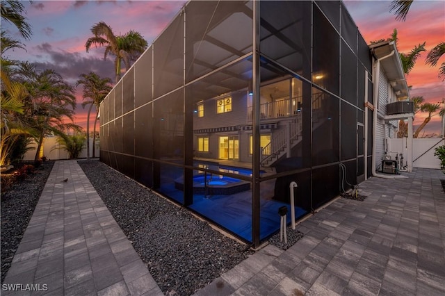 property exterior at dusk with a patio and glass enclosure