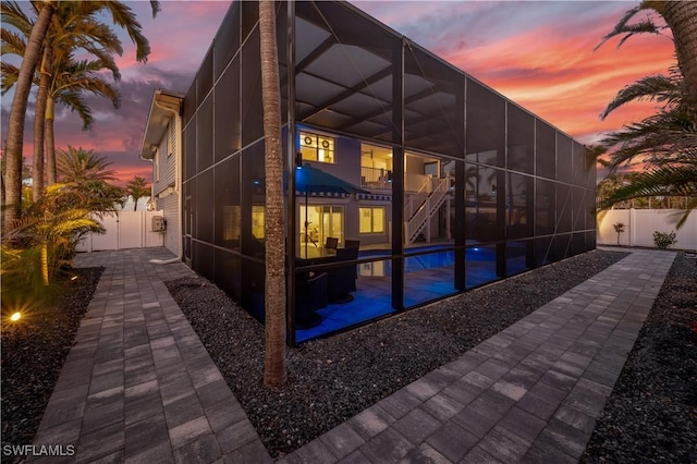 property exterior at dusk with a lanai and a patio area