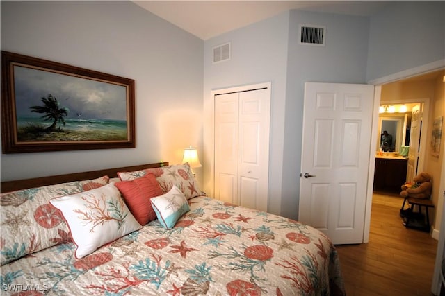 bedroom with vaulted ceiling, hardwood / wood-style flooring, and a closet