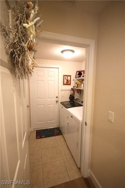 clothes washing area featuring washing machine and dryer and light tile patterned flooring