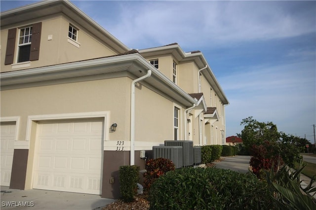 view of home's exterior with central AC unit and a garage