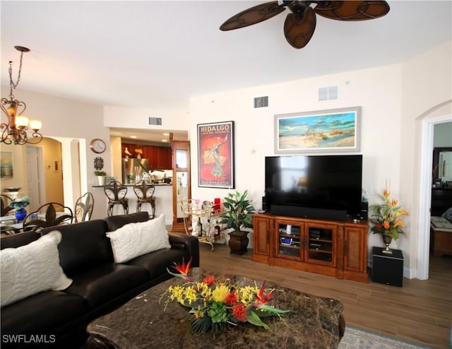 living room featuring ceiling fan with notable chandelier and hardwood / wood-style flooring