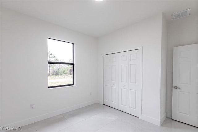 unfurnished bedroom featuring light tile patterned floors and a closet