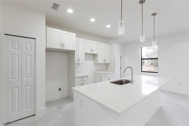 kitchen featuring hanging light fixtures, sink, a center island with sink, and white cabinets