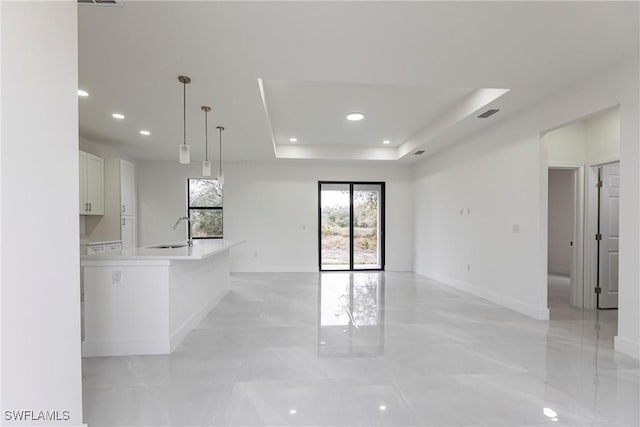 unfurnished living room with sink and a raised ceiling