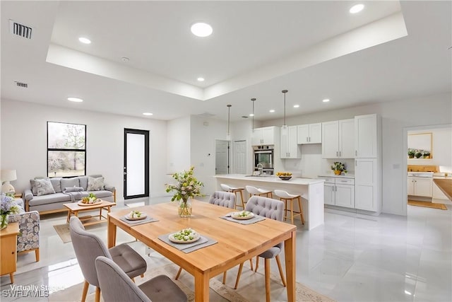 tiled dining space with a raised ceiling